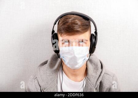 Jeune homme irrité dans le casque et le masque de grippe par le Mur dans la chambre Banque D'Images