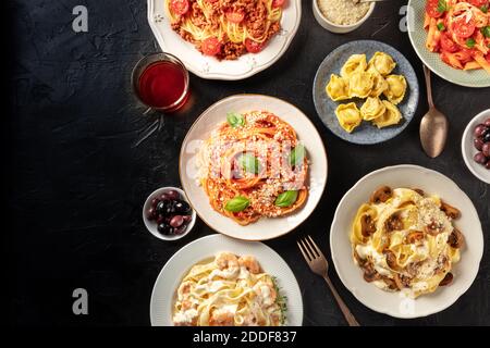 Modèle de banderole italienne pour pâtes avec espace de copie. Un plat d'un assortiment de plats de pâtes avec du vin et des olives, tiré du dessus sur un fond sombre Banque D'Images