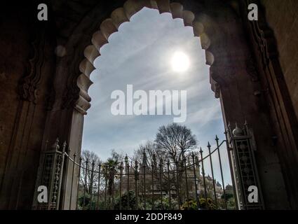 Le soleil d'hiver brille à travers la porte d'entrée de style indien dans les jardins donnant une impression abstraite de la forme de l'arche. Banque D'Images