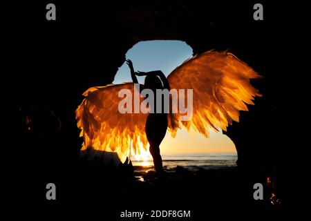 San Diego, Californie, États-Unis. 15 novembre 2020. Une femme tient des ailes alors qu'elle se tient dans une grotte des Sunset Cliffs à San Diego, tandis que le soleil se couche lors d'une chaude journée d'automne. Crédit : K.C. Actualités en direct Alfred/ZUMA Wire/Alay Banque D'Images