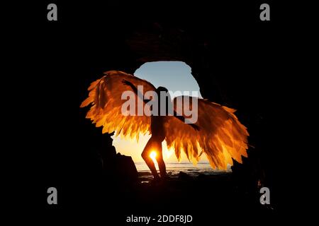 San Diego, Californie, États-Unis. 15 novembre 2020. Une femme tient des ailes alors qu'elle se tient dans une grotte des Sunset Cliffs à San Diego, tandis que le soleil se couche lors d'une chaude journée d'automne. Crédit : K.C. Actualités en direct Alfred/ZUMA Wire/Alay Banque D'Images