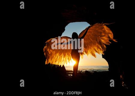 San Diego, Californie, États-Unis. 15 novembre 2020. Une femme tient des ailes alors qu'elle se tient dans une grotte des Sunset Cliffs à San Diego, tandis que le soleil se couche lors d'une chaude journée d'automne. Crédit : K.C. Actualités en direct Alfred/ZUMA Wire/Alay Banque D'Images