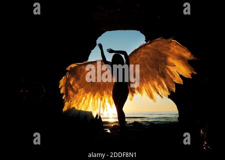 San Diego, Californie, États-Unis. 15 novembre 2020. Une femme tient des ailes alors qu'elle se tient dans une grotte des Sunset Cliffs à San Diego, tandis que le soleil se couche lors d'une chaude journée d'automne. Crédit : K.C. Actualités en direct Alfred/ZUMA Wire/Alay Banque D'Images