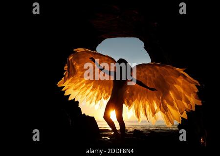 San Diego, Californie, États-Unis. 15 novembre 2020. Une femme tient des ailes alors qu'elle se tient dans une grotte des Sunset Cliffs à San Diego, tandis que le soleil se couche lors d'une chaude journée d'automne. Crédit : K.C. Actualités en direct Alfred/ZUMA Wire/Alay Banque D'Images