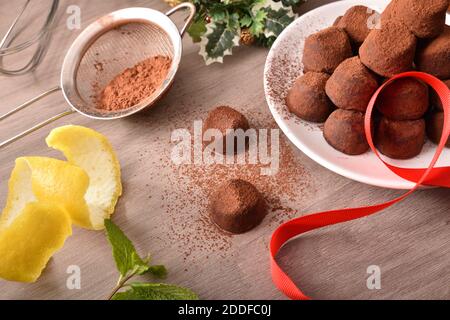 Truffes au chocolat avec poudre de cacao pour un événement sur un banc en bois avec des ingrédients et des outils. Vue en hauteur. Composition horizontale. Banque D'Images