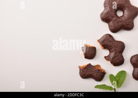 Biscuits trempés dans des chocolats en forme d'étoile sur une table blanche avec des feuilles de menthe. Vue de dessus. Composition horizontale. Banque D'Images