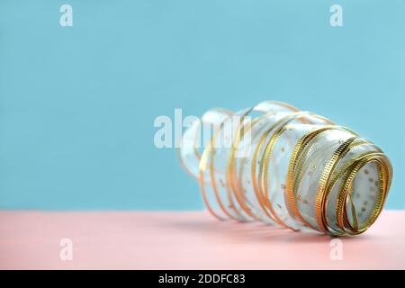 emballage ruban doré pour décor de cadeau sur fond rose et bleu. douche pour bébé, emballage cadeau anniversaire ou noël. ruban à fils texturé festif. Banque D'Images