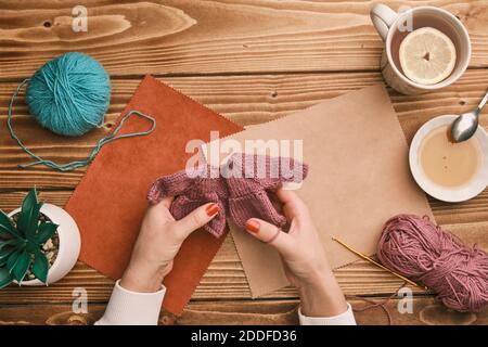 Des mains de femmes triant des vêtements de poupée sur une table en bois à domicile en quarantaine Banque D'Images