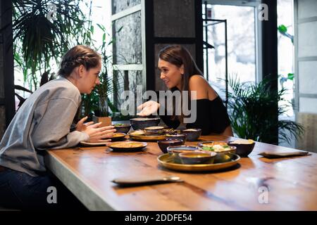 Deux jolies filles d'école secondaire qui persiflent dans un café. Banque D'Images