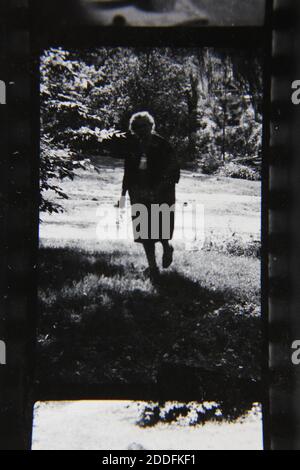 Belle photographie en noir et blanc vintage des années 1970 d'une femme âgée qui profite de son temps dans son arrière-cour. Banque D'Images