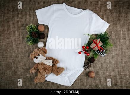 Cache-cache blanc blanc pour bébé Noël. Body style une pièce pour bébé avec vue sur le dessus sur un fond rustique. Copier l'espace. Annonce bébé. Banque D'Images