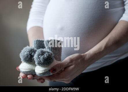 Gros plan d'une femme enceinte tenant des chaussettes de bébé tricotées. Concept bientôt disponible. Mère attendue au cours du dernier trimestre. Banque D'Images