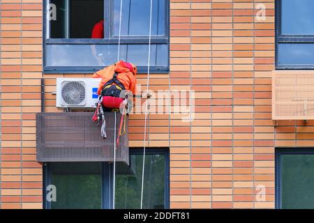 Un grimpeur en activité installe un climatiseur pour un appartement dans un bâtiment de plusieurs étages - Moscou, Russie, le 18 juin 2020 Banque D'Images