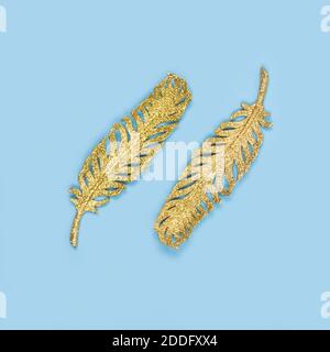 Golden ornements - feuilles tropicales exotiques sur fond bleu pastel. Flat lay, concept de fête minimaliste. Concept de bijoux créatifs, concentration sélective Banque D'Images
