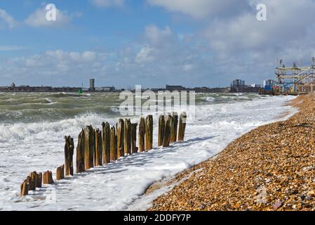 Mer d'hiver agitée, avec des vagues se brisant sur le front de mer à Southsea, Portsmouth, Hants, avec Clarence Pier au loin Banque D'Images