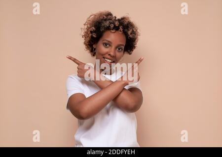 Femme africaine remplie d'hésitations et de doutes, points avec index dans les différents côtés, montre deux manières à gauche et à droite. Prise de vue en studio Banque D'Images