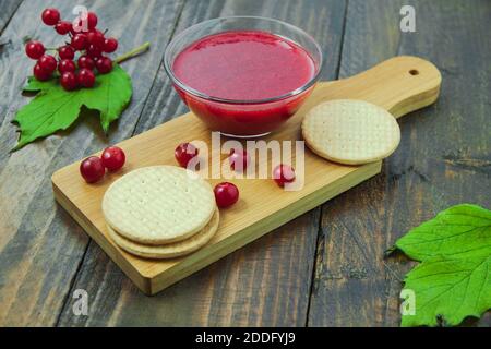 Confiture de Viburnum avec biscuits sur panneau de bois décoré de branches, feuilles. Composition d'automne. Concept de petit déjeuner Banque D'Images