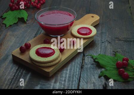 Confiture de Viburnum avec biscuits sur panneau de bois décoré de branches, feuilles. Composition d'automne. Concept de petit déjeuner Banque D'Images