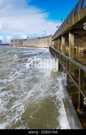 Vue sur le front de mer à Old Portsmouth, Hants, pendant une tempête hivernale agitée, avec des vagues se brisant contre le digue en face de la tour carrée. Banque D'Images