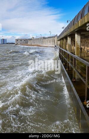 Vue sur le front de mer à Old Portsmouth, Hants, pendant une tempête hivernale agitée, avec des vagues se brisant contre le digue en face de la tour carrée. Banque D'Images