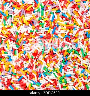 Arc-en-ciel, fond et surface carrés. Saupoudrer de sucre coloré en forme de tige. Bonbons minuscules dans une variété de couleurs, utilisés comme garniture. Banque D'Images
