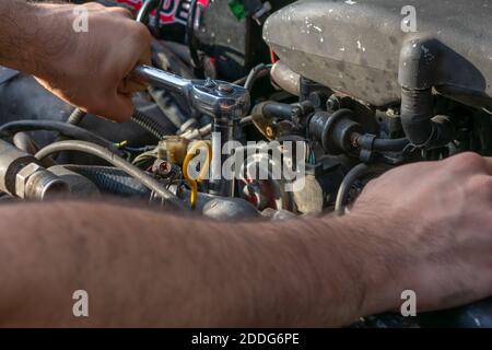Un gros plan des mains de hommes qui réparent une voiture Banque D'Images