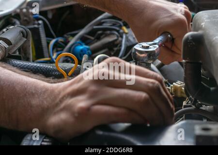 Un gros plan des mains de hommes qui réparent une voiture Banque D'Images