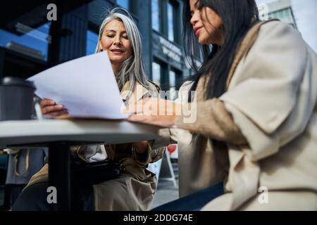 Deux femmes d'affaires élégantes étudiant des documents dans un café extérieur Banque D'Images