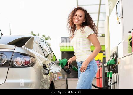 Femme afro-américaine remplissant le réservoir de voiture à la station-service Banque D'Images