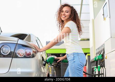 Femme afro-américaine remplissant le réservoir de voiture à la station-service Banque D'Images