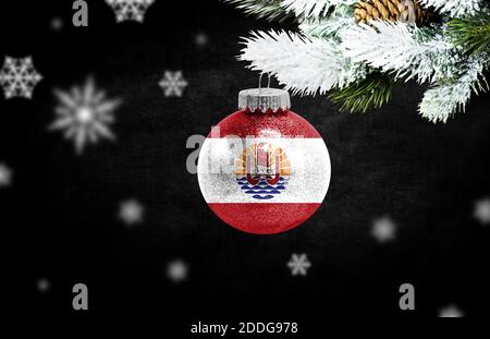 Bonne année 2021, drapeau de la Polynésie française sur un jouet de noël, décorations isolées sur fond sombre. Concept de noël créatif. Banque D'Images