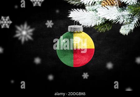 Bonne année 2021, drapeau du Bénin sur un jouet de noël, décorations isolées sur fond sombre. Concept de noël créatif. Banque D'Images