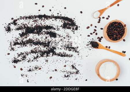 Gommage maison avec grains de café moulus et sel de mer, produit biologique naturel éparpillé sur une table blanche, plat. Banque D'Images
