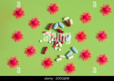 Les virus entourent une pile de pilules sur une table verte. Particules de simulation COVID-19 avec certains médicaments sur fond vert. Concept de soins de santé. Banque D'Images