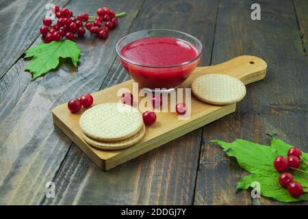 Confiture de Viburnum avec biscuits sur panneau de bois décoré de branches, feuilles. Composition d'automne. Concept de petit déjeuner Banque D'Images