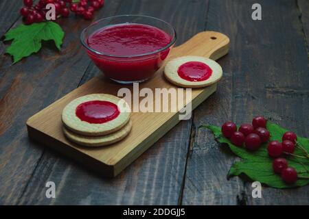 Confiture de Viburnum avec biscuits sur panneau de bois décoré de branches, feuilles. Composition d'automne. Concept de petit déjeuner Banque D'Images