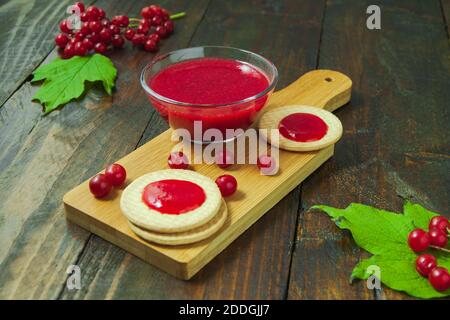 Confiture de Viburnum avec biscuits sur panneau de bois décoré de branches, feuilles. Composition d'automne. Concept de petit déjeuner Banque D'Images