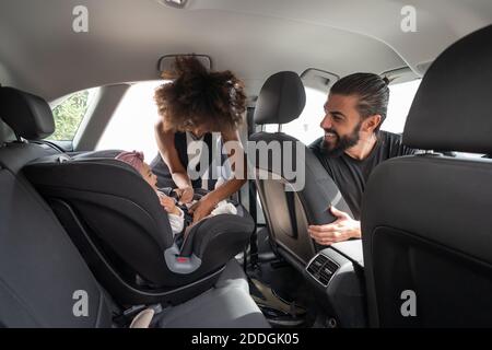 Mère afro-américaine attentionnée mettant tendre un tout-petit mignon dans un cadre moderne siège d'auto pour bébé Banque D'Images