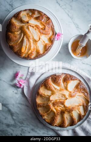 Composition vue de dessus avec de délicieux gâteaux aux pommes faits maison sur les assiettes placées sur la table avec un bol de sirop doux et brosse de cuisson Banque D'Images