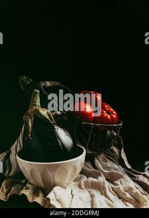 Tomates rouges mûres fraîches et courgettes vertes avec aubergine bols placés sur la table de cuisine lors de la préparation d'un végétarien sain plat Banque D'Images