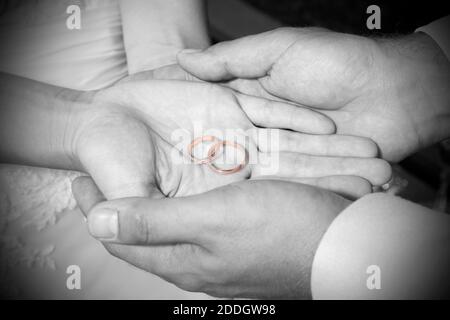 Une photo en niveaux de gris des mains tenant des anneaux de mariage Banque D'Images