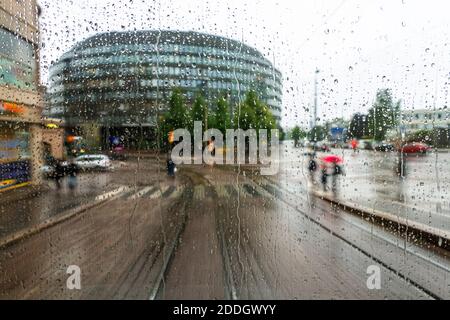 Helsinki, Finlande. Prendre le tram dans le centre-ville d'Helsinki, la capitale de la Finlande. Circulation en voiture et en tramway. Jour pluvieux nuageux, de nombreux magasins, cafés. Pluie Banque D'Images