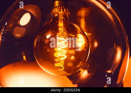 Lampe de style vintage à l'intérieur d'une spirale électrique en lumière chaude avec reflet sur double verre, vue rapprochée Banque D'Images