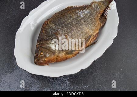 Gros plan de poisson frit sur un plateau blanc . Arrière-plan clair, Banque D'Images