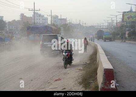 Les gens marchent sur une route poussiéreuse très fréquentée à Dhaka, au Bangladesh, le 25 novembre 2020. L'état de l'air de la ville de Dhaka s'aggrave jour après jour en cas d'alarme Banque D'Images