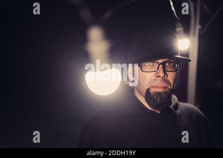 Gros plan d'un homme barbu à capuche noire lunettes et capuchon avec lumières Banque D'Images