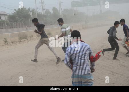 Les gens marchent sur une route poussiéreuse très fréquentée à Dhaka, au Bangladesh, le 25 novembre 2020. L'état de l'air de la ville de Dhaka s'aggrave jour après jour en cas d'alarme Banque D'Images