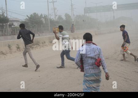 Les gens marchent sur une route poussiéreuse très fréquentée à Dhaka, au Bangladesh, le 25 novembre 2020. L'état de l'air de la ville de Dhaka s'aggrave jour après jour en cas d'alarme Banque D'Images