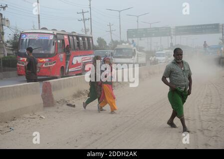 Les gens marchent sur une route poussiéreuse très fréquentée à Dhaka, au Bangladesh, le 25 novembre 2020. L'état de l'air de la ville de Dhaka s'aggrave jour après jour en cas d'alarme Banque D'Images