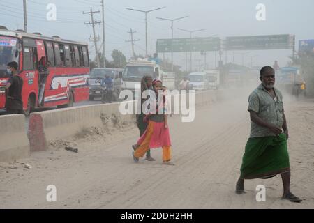 Les gens marchent sur une route poussiéreuse très fréquentée à Dhaka, au Bangladesh, le 25 novembre 2020. L'état de l'air de la ville de Dhaka s'aggrave jour après jour en cas d'alarme Banque D'Images